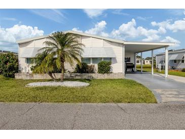 Charming single-story home featuring a carport, well-manicured lawn, and lovely palm tree at 425 Pirates Pt, North Port, FL 34287