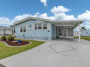 Charming single-story home with light blue siding, complemented by a well-maintained lawn and covered parking at 443 Landsedge Dr, North Port, FL 34287
