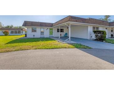 Cozy home with white exterior, front yard, and covered parking spot with blue chair at 680 Circlewood Dr # W3, Venice, FL 34293