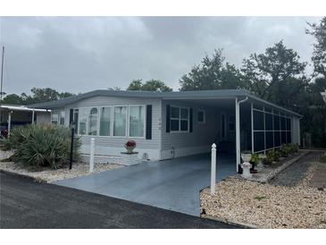 Charming mobile home featuring neutral tones, a screened porch, and a carport with decorative landscaping at 795 Cervina N Dr, Venice, FL 34285