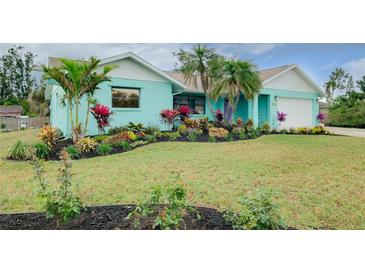 Charming single-story home with colorful landscaping, palm trees, and an attached two-car garage at 990 Sea Fox Rd, Venice, FL 34293
