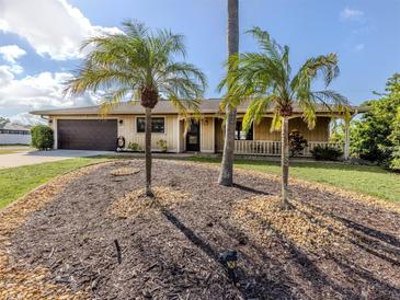 Charming single story home featuring mature palms, a two-car garage and a covered front porch at 1101 Southland Rd, Venice, FL 34293