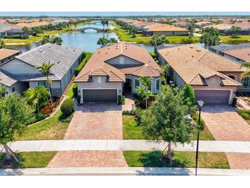 Stunning aerial view of home with beautiful landscaping, lake view and brick driveway at 13511 Esposito St, Venice, FL 34293