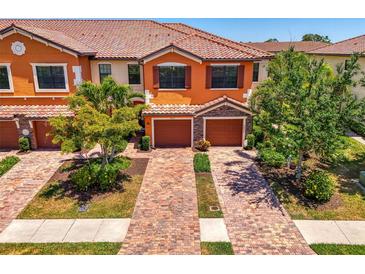 Charming two-story townhome featuring a clay tile roof, brick driveway, and attached two-car garage at 20237 Lagente Cir, Venice, FL 34293