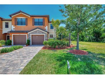 Charming townhome with brick paver driveway, two-car garage, and lush landscaping at 20290 Lagente Cir, Venice, FL 34293