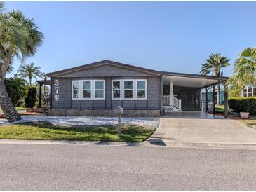 Charming home featuring well-maintained landscaping, a covered carport and gray siding for a polished look at 379 Harbor Isles Dr, North Port, FL 34287