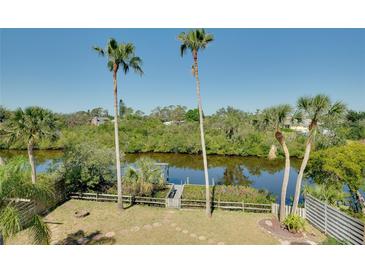 A backyard view with a waterway, a private dock, palm trees, lush greenery, and a fire pit at 610 Alligator Dr, Venice, FL 34293