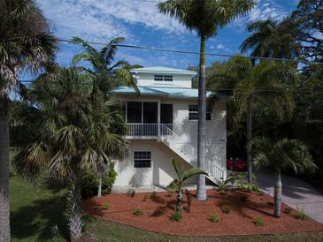 Two-story home featuring a screened-in porch, white stairs and a vibrant lawn at 770 Yale St, Englewood, FL 34223