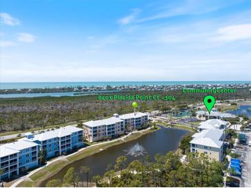 Aerial view of a condo community with waterfront views, a lake with a fountain, and well-maintained landscaping at 8403 Placida Rd # 304, Placida, FL 33946