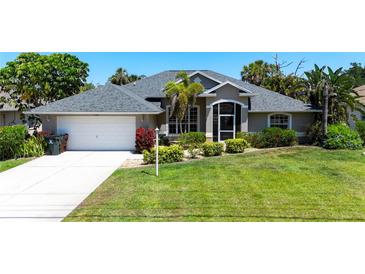 Charming home boasts mature landscaping, a two-car garage, and a well-maintained lawn at 1124 W Hillsborough Blvd, North Port, FL 34288