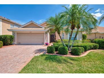 Charming single-story home with a brick driveway, lush landscaping, and a two-car garage at 11437 Dancing River Dr, Venice, FL 34292