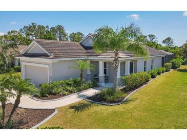 Charming single-story home with a well-manicured lawn, lush landscaping, and a welcoming covered porch at 11455 Fort Lauderdale Pl, Venice, FL 34293