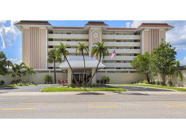 Elegant multi-story condo building featuring well-manicured landscaping and a charming entrance area with an American flag at 1150 Tarpon Center Dr # 3G 307, Venice, FL 34285