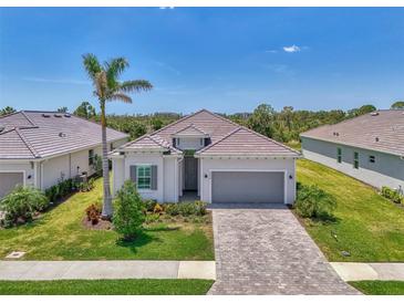 Charming single-story home features a tile roof, a paved driveway, a two-car garage and lush landscaping at 17515 Jadestone Ct, Venice, FL 34293