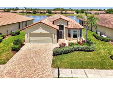 Inviting single-story home with a red tile roof, manicured lawn, and a brick driveway leading to the garage at 20246 Pezzana Dr, Venice, FL 34292