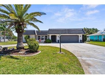 Charming single Gathering home with lush lawn, mature palm tree, and a two-car garage at 205 Cavallini Dr, Nokomis, FL 34275