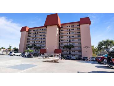 Spacious condo building with a light exterior, parking, and palm trees against a blue sky at 244 Saint Augustine # 605, Venice, FL 34285