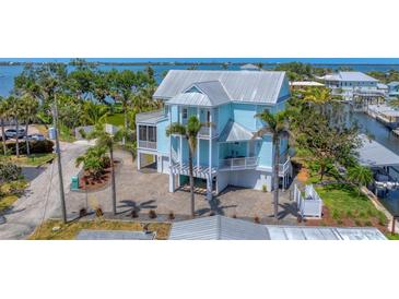 Beautiful waterfront home with a metal roof, multiple balconies, and a lush, tropical landscape at 320 O Day, Englewood, FL 34223