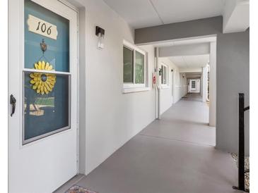 Exterior condo hallway with unit 106 featuring a white door, welcome decoration, and a covered walkway at 649 Tamiami S Trl # 106, Venice, FL 34285