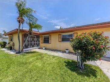 Charming home with a well-maintained lawn, tropical plants, and decorative shutters at 1320 Whispering Ln, Venice, FL 34285