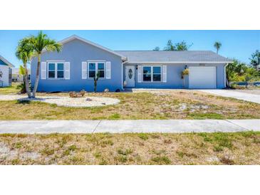 Charming single-story home featuring a light blue exterior and well-maintained front yard, perfect for curb appeal at 13579 Romford Ave, Port Charlotte, FL 33981