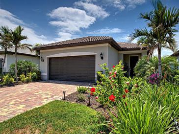 Charming home featuring a two-car garage, lush landscaping and a brick driveway at 13731 Vadini St, Venice, FL 34293