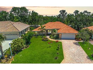 Charming single-story home boasting lush landscaping, brick driveway, and a vibrant orange tile roof at 4856 Jacaranda Heights Dr, Venice, FL 34293