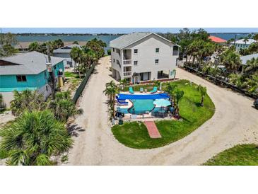 An aerial view of a home's backyard, featuring a private pool with lounge chairs and a grassy area with palm trees at 5031 N Beach Rd # 118, Englewood, FL 34223