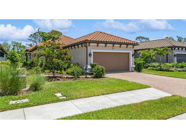 Charming home featuring a tile roof, well-manicured landscaping, and a brown two-car garage at 5856 Semolino St, Nokomis, FL 34275