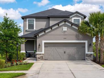 Charming two-story home featuring a spacious two-car garage, palm tree, and beautifully landscaped front yard at 8304 Shooting Star Rd, Sarasota, FL 34241