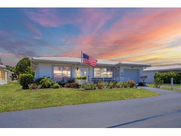 Charming single-story home with an American flag, lush lawn, and well-maintained landscaping at 8701 Pickwick Rd, North Port, FL 34287