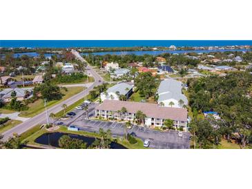 Beautiful aerial view of the condo complex with lush landscaping, community pond, and Gulf views at 1730 Manasota Beach Rd # 212, Englewood, FL 34223