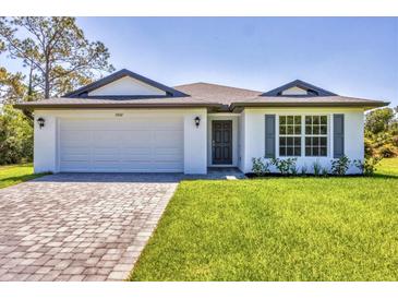Beautiful single-story home featuring a neatly paved driveway and a well-manicured lawn at 2032 Jagust Rd, North Port, FL 34288