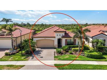 Charming single-story home with a red tile roof, lush landscaping, and a two-car garage at 23493 Copperleaf Dr, Venice, FL 34293