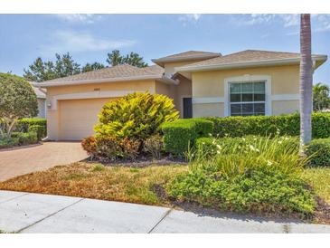 Inviting single-story home with a well-manicured lawn and a paver driveway leading to the attached two-car garage at 24849 Pennington Ter, Venice, FL 34293