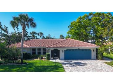 Charming single-story home with a well-manicured lawn, blue garage door, and a brick driveway at 316 Signorelli Dr, Nokomis, FL 34275