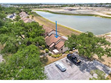 Beautiful aerial view of townhouse with parking, mature landscaping, and serene lake views at 5559 Brassy Loop, North Port, FL 34287