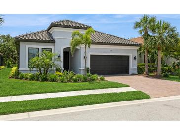 Beautiful single Gathering home with a tile roof, paver driveway, manicured lawn and tropical landscaping at 5581 Piccolo St, Nokomis, FL 34275
