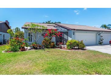 Charming home with lush landscaping, colorful flowers, and a well-maintained lawn at 657 Foxwood Blvd, Englewood, FL 34223