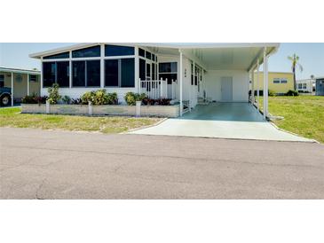 Charming home featuring a covered carport, front porch with an enclosed sunroom, and manicured landscaping at 304 Roma Rd, Venice, FL 34285