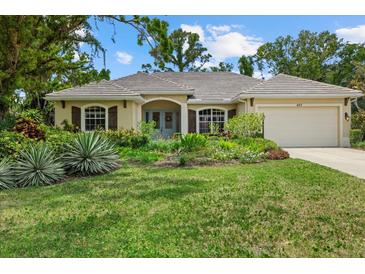 Charming home with lush landscaping, a well-maintained lawn, and a welcoming facade at 427 Autumn Chase Dr, Venice, FL 34292