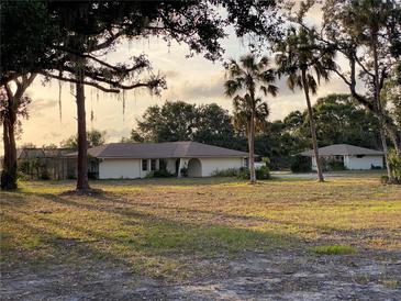 Lovely single-story home with neutral tones surrounded by luscious landscaping and stately palm trees at 5760 Howard Creek Rd, Sarasota, FL 34241