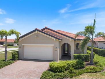 Charming single-story home featuring a red tile roof, lush landscaping, and a brick driveway at 10209 Fiddlewood Dr, Venice, FL 34293