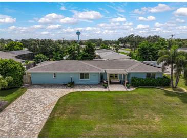 Charming light blue home features a well-manicured lawn, a brick driveway, and a cozy pergola-covered seating area at 1099 Nokomis S Ave, Venice, FL 34285