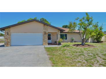 Charming single-story home with a two-car garage, beige exterior, and well-manicured lawn at 1203 Hudson Rd, Venice, FL 34293