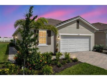 Charming single-story home featuring a well-manicured lawn and a two-car garage with brick paved drive at 12538 Somatic Ct, Venice, FL 34293