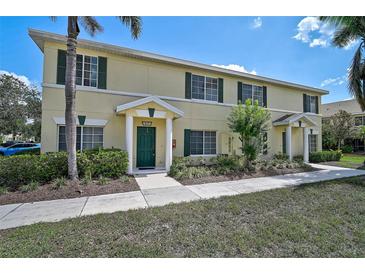 Well-maintained, two-story townhouse featuring a green door, dark shutters, and lush landscaping at 233 Cape Harbour Loop # 107, Bradenton, FL 34212