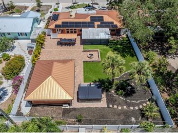 Aerial view of a home showing a large backyard with a fire pit, putting green and a covered patio with outdoor seating at 409 Armada S Rd, Venice, FL 34285