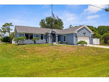 Charming blue single-story home featuring a well-manicured lawn and attached two-car garage at 4305 Heyward St, North Port, FL 34291