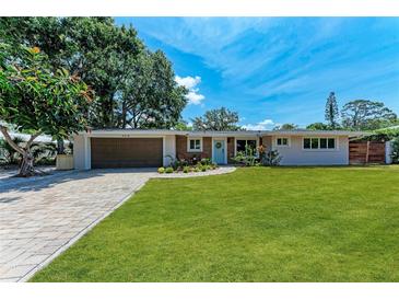 Charming single-story home featuring a manicured lawn, brick driveway, and a quaint front garden at 4616 Leeta Ln, Sarasota, FL 34234